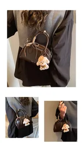 Detail of dark brown vintage Boston bag with plush dog charm and plaid ribbon bow