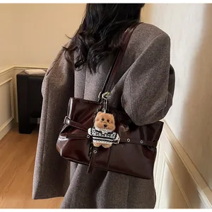 Détail d'un grand cabas en cuir ciré marron foncé avec boucle et pendentif d'ours