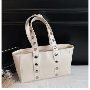 Close-up of cream shoulder bag with textured leather and metallic rivet details