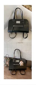 Detail of black vintage tote bag with glossy leather finish and plush puppy charm
