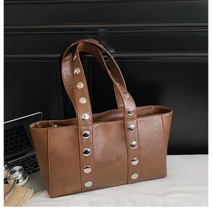 Close-up of brown PU leather tote with silver metal rivets and a secure zipper closure