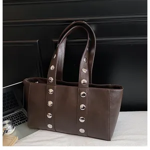 Detailed view of dark brown faux leather bag featuring silver round metal rivets and strap