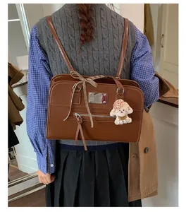 Close-up of vintage brown tote bag with ribbon bow and cute plush puppy charm detail