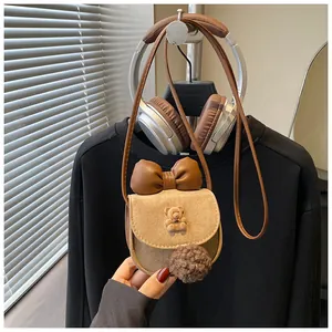 Dettaglio della graziosa borsa a tracolla kaki per bambina con fiocco in pelle e ciondolo a orso