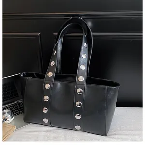 Detail of black faux leather tote with silver rivets and polished texture for work