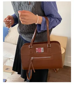 Detail view of large brown vintage tote bag with front zipper pocket and metal accent
