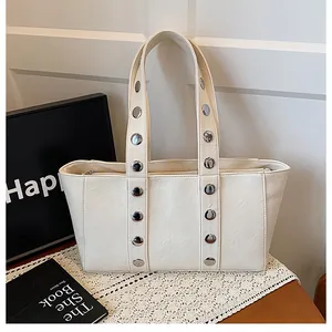 Detail shot of cream leather tote bag featuring silver rivets and pebbled texture