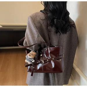 Détail du sac cabas en cuir ciré bordeaux avec texture plissée et charmant pendentif d'ours