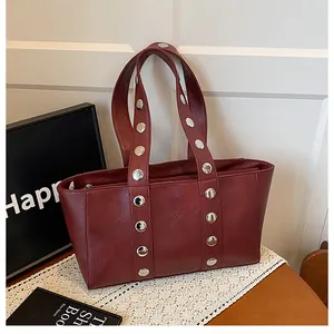 Detailed macro view of dark red PU leather shoulder bag with silver rivet studs on strap