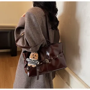 Détail du sac cabas en cuir ciré marron foncé avec boucle en métal et breloque ours