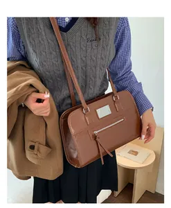 Detail of vintage brown tote bag featuring front zipper pocket and glossy texture