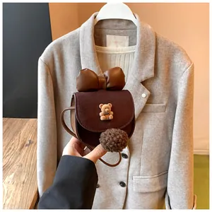 Dettaglio borsa a tracolla bimba marrone con orsetto 3D, fiocco e ciondolo a pompon