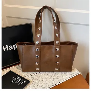 Detail of vintage brown tote bag featuring metallic silver rivets and smooth leather texture