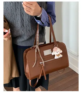 Detail of vintage brown tote bag featuring zipper pocket, bow, and plush dog charm