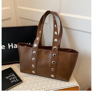 Detail view of large silver metal studs on dark brown faux leather tote bag strap
