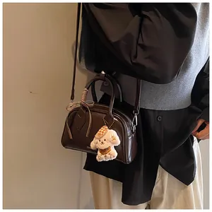 Detail of dark brown vintage Boston bag with a checkered ribbon and cute dog plush pendant