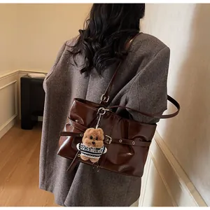 Détail du sac cabas en cuir ciré marron foncé avec boucles argentées et pendentif d'ours