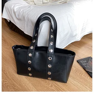 Detail of black PU leather tote bag with silver studs on straps and clear texture