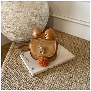 Dettaglio mini borsa a tracolla marrone in camoscio con fiocco in pelle e decoro orsetto