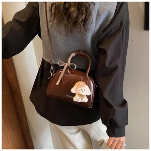 Detail of vintage brown leather Boston bag with plush dog charm and plaid ribbon bow