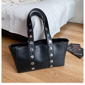 Detail of matte black leather handbag with silver metal rivets and secure zipper closure