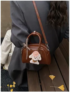 Brown Boston bag with plaid bow and white puppy charm shown in an autumn street setting