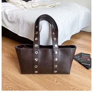 Detail of silver rivets on dark brown faux leather shoulder strap of a tote bag