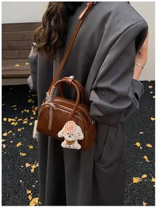 Detail of vintage brown leather Boston bag with plush dog charm and bow accessory