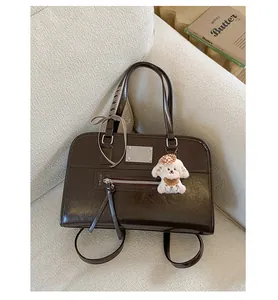 Detail of dark brown wax leather tote with a plaid bow and cute plush dog charm