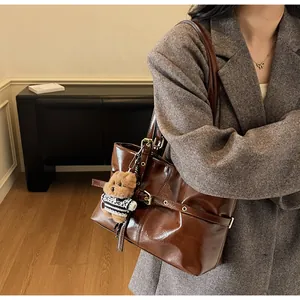 Détail du cabas en cuir ciré marron foncé avec boucle métallique et breloque en peluche