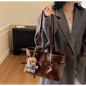 Détail d'un grand cabas en cuir ciré marron foncé avec boucle et pendentif ours