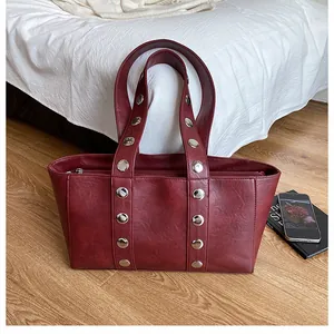 Detail view of burgundy PU leather tote with silver metal rivets and wide handle