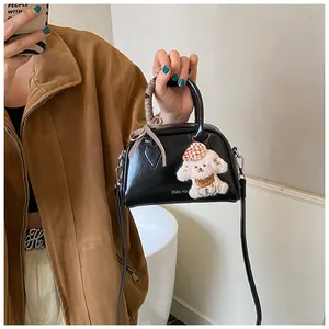 Detail of black glossy vintage pillow bag featuring logo print and cute plush dog pendant