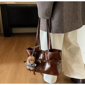 Détail du sac cabas en cuir ciré marron foncé avec un porte-clés ours en peluche mignon