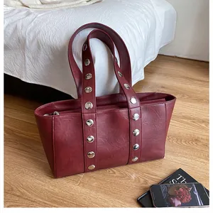 Detailed view of silver metal rivets on a dark red faux leather tote shoulder bag