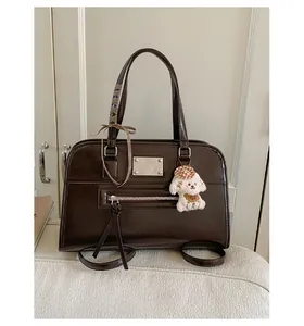Detail of dark brown leather tote bag with silver plaque, plaid ribbon and puppy charm