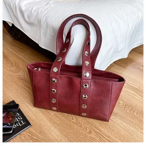 Close-up of wine red synthetic leather tote bag with stylish silver metal rivets detail