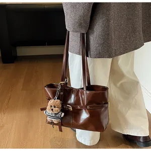 Détail d'un sac cabas en cuir ciré marron foncé avec un porte-clés ours en peluche
