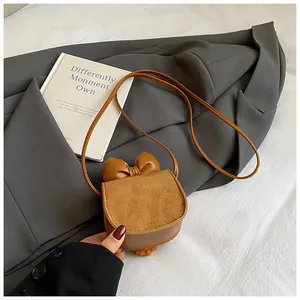 Dettaglio borsa a tracolla marrone con fiocco e texture miste su blazer grigio