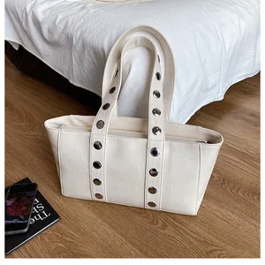 Detailed view of cream PU leather tote with silver metal studs and zipper closure