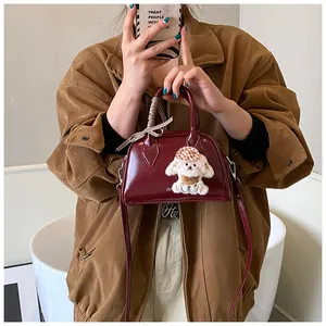 Mirror selfie showing a burgundy patent leather mini Boston bag with a cute dog pendant