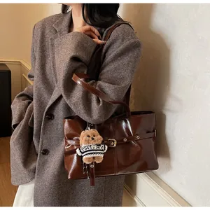 Détail du sac cabas en cuir ciré marron foncé avec sangle et pendentif ours