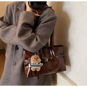 Détail du sac cabas en cuir marron foncé brillant avec un charmant pendentif caniche