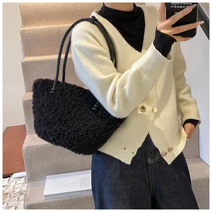 Detail view of black faux shearling tote bag styled with casual knitwear and blue jeans