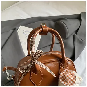 Detailed view of a brown vintage boston bag with checkered bow and plush charm