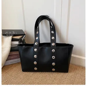 Close-up of textured black leather tote bag featuring stylish silver metal rivets and straps