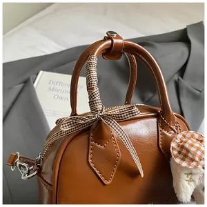 Detail of vintage brown Boston bag with checkered scarf and white plush doll charm