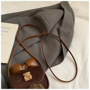 Dettaglio borsa a tracolla per bambini con orsetto di peluche, fiocco e texture opaca