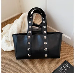 Detailed close-up of a black tote bag featuring stylish silver metal studs on the shoulder strap