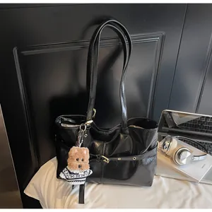 Détail du cabas en cuir ciré noir avec œillets dorés et breloque en peluche pour chien